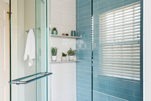 shower with light blue glass subway wall tile, shelf, window