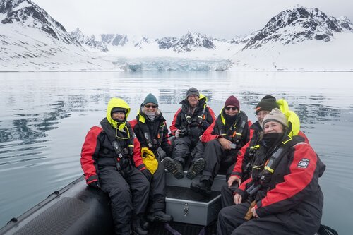 Happy guests on zodiac cruise Svalbard mountain backdrop Secret Atlas