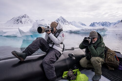 Woman taking a photo with a large lens. Icy mountain backdrop Secret Atlas