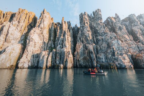 Zodiac infront of bird cliffs in Svalbard, Secret Atlas