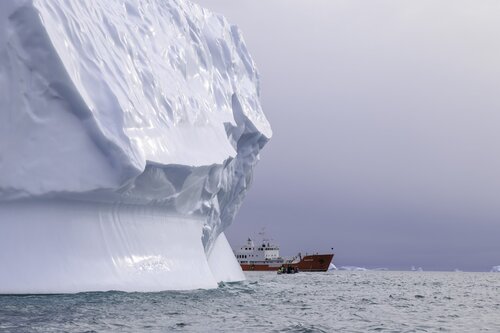 Ship coming out from behind an iceberg Greenland Secret Atlas