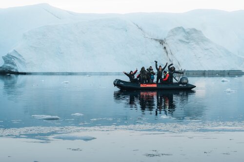 People on a boat in Greenland by a Glacier snow mountain. Zodiac Cruise Secret Atlas