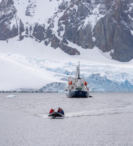Ship sailing in icy waters with snow capped mountain backdrop Secret Atlas