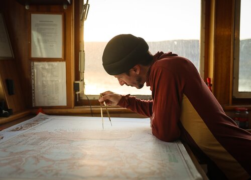 Man looking at a map on the Bridge of a ship Secret Atlas