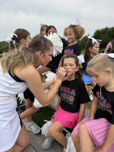 Varsity cheerleaders helping elementary cheerleaders during the football game