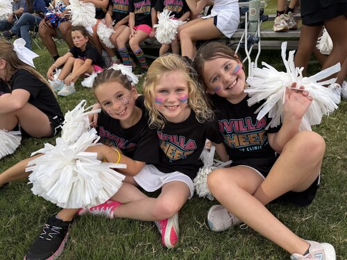 Varsity cheerleaders helping elementary cheerleaders during the football game