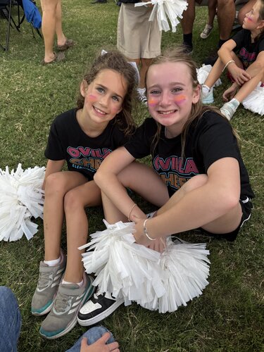 Varsity cheerleaders helping elementary cheerleaders during the football game