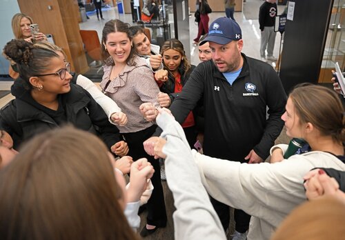 Interim women’s basketball coach Brett Zanardi circles his team to cheer after watching a Peace and Conflict pathway panel session with teammate Charlotte Head ’26 presenting “What Determines the Success of an International Organization?”, and Emily Brankman ’26 presenting “How Do Masculine Perceptions of Leadership Shape the Behavior of Female Politicians?” Andrew Harding ’26 presenting “Can Understanding and Addressing the Roots of Conflict Produce a Lasting Peace?”  Anna Taylor ’26 presenting “How Have Political Extremists Weaponized Classical History, and Why Does It Matter?” at the seventh annual All-College Symposium Thursday, November 6, 2025. (Connecticut College photos by Sean D. Elliot)