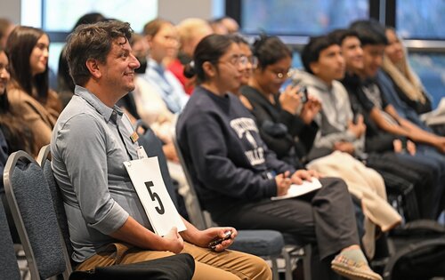 Timekeeper Scott D'Agostino gives a speaker updates during the CISLA panel session with Anna Olivia Nielsen ’26 “Comparing the Integration of Ukrainian and Other Single Refugee Women in Germany”,  Stephanie Reyes Bravo ’26 “Más que madres: Maternal Health and the Invisible Struggles of Motherhood”, Eisha Giran ’26 “Invisible Shipwrecks & Neurological Endangerment: The Trade-Off in Seeking Asylum”,  Delaney Brenner ’26 “Decolonizing Health in Madagascar: A Francophone Perspective”at the seventh annual All-College Symposium Thursday, November 6, 2025. (Connecticut College photos by Sean D. Elliot)