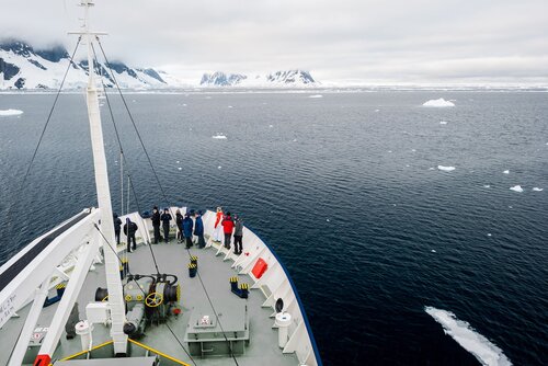 DNY473 Lemaire Channel Cruise Ship Passengers Antarctica // Passengers stand out on the bow of a cruise ship to admire the view when passing through the Lemaire Channel, sometimes known as Kodak Gap for its scenic views.