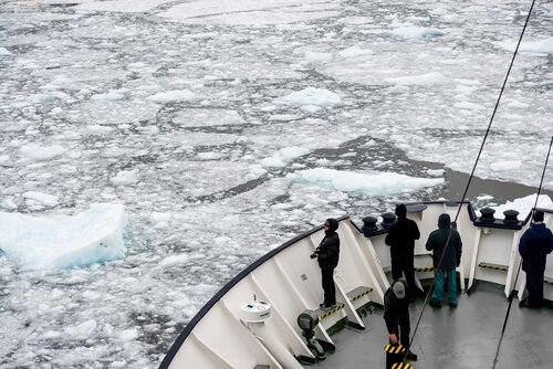 DNY5CM Lemaire Channel Antarctic Peninsula Cruise Ship Passengers // Passengers stand on the bow of an ice-strengthened Antarctic cruise ship as it navigates the narrow Lemaire Channel on the western side of the Antarctic Peninsula. The Lemaire Channel is sometimes referred to as Kodak Gap in a nod to its famously scenic views.