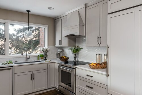 cabinet color: Accessible Beige by Sherwin williams, custom hood vent, backsplash tile, panel refrigerator, pendant light
