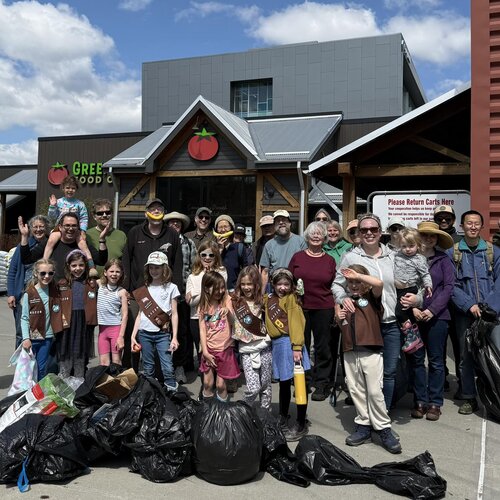 A group of GreenStar shoppers and community members stands proudly behind the multiple bags of trash they cleaned up during this annual event.