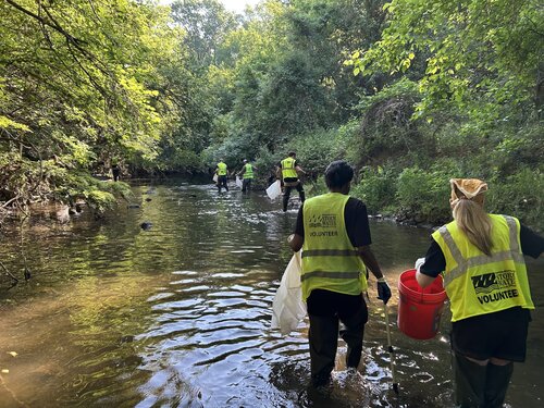 Volunteers gather to remove litter from Little Sugar Creek and clear and mark storm drains.