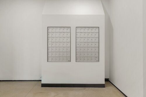 The image depicts a minimalist and modern interior setting featuring a white wall with two large, rectangular grids of mailboxes mounted side by side. Each grid contains multiple small, square compartments, each with a small lock and a number, suggesting they are used for mail or package storage. The mailboxes are metallic, adding a subtle sheen against the otherwise matte white wall.

The setting appears to be a lobby or hallway, possibly in an apartment building or office complex, given the organized and utilitarian design. The floor is a light, polished stone or tile, complementing the clean and uncluttered aesthetic of the space. The lighting is bright and even, with no shadows, suggesting overhead fluorescent or LED lights.

The atmosphere is neutral and functional, with a focus on practicality and order. The design is contemporary, emphasizing simplicity and efficiency. There are no people or additional objects in the scene, which enhances the sense of calm and orderliness. The image conveys a sense of modern urban living or working environment, where such mailboxes are a common feature.

[AI]
The image depicts a minimalist, modern interior space featuring a wall-mounted installation of two grids of mailboxes. These mailboxes are metallic and uniform in appearance, each with a small lock and a number label, suggesting a setting such as an apartment building, office, or post office. The wall and surrounding area are painted in a clean, bright white, contributing to a sterile and organized atmosphere. The floor is a light beige or off-white, adding to the neutral color palette. The lighting is bright and even, likely from overhead sources, emphasizing the orderly and functional nature of the space. The overall ambiance is one of simplicity and efficiency, with a focus on utility and order. There are no visible individuals or additional objects, reinforcing the theme of functionality and the routine nature of mail collection.